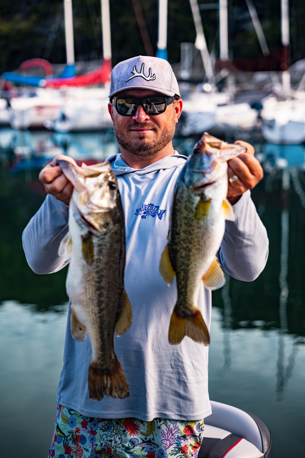 Chris Studinger holding up two largemouth bass in front of a Central Texas marina