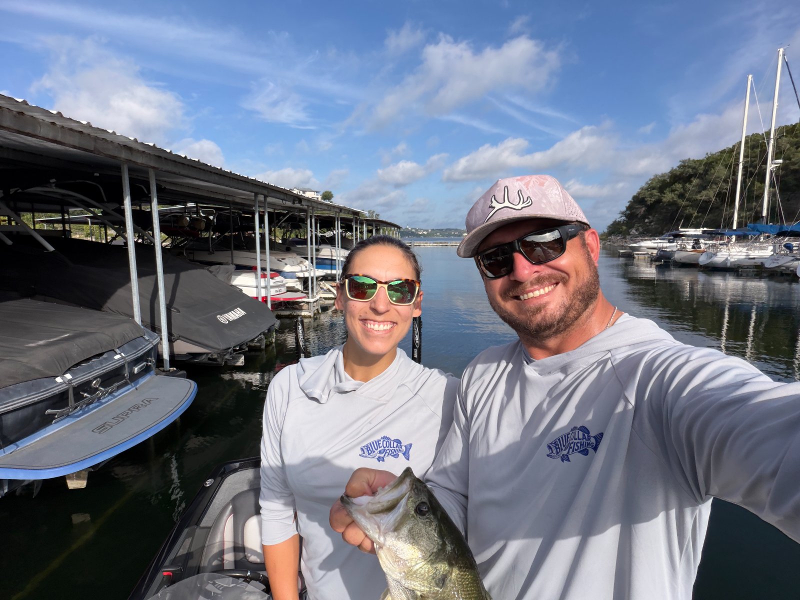 Two anglers in Blue Collar Fishing shirts with a bass at the Lake Travis marina